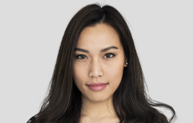 A woman standing in a hallway holding documents and smiling.